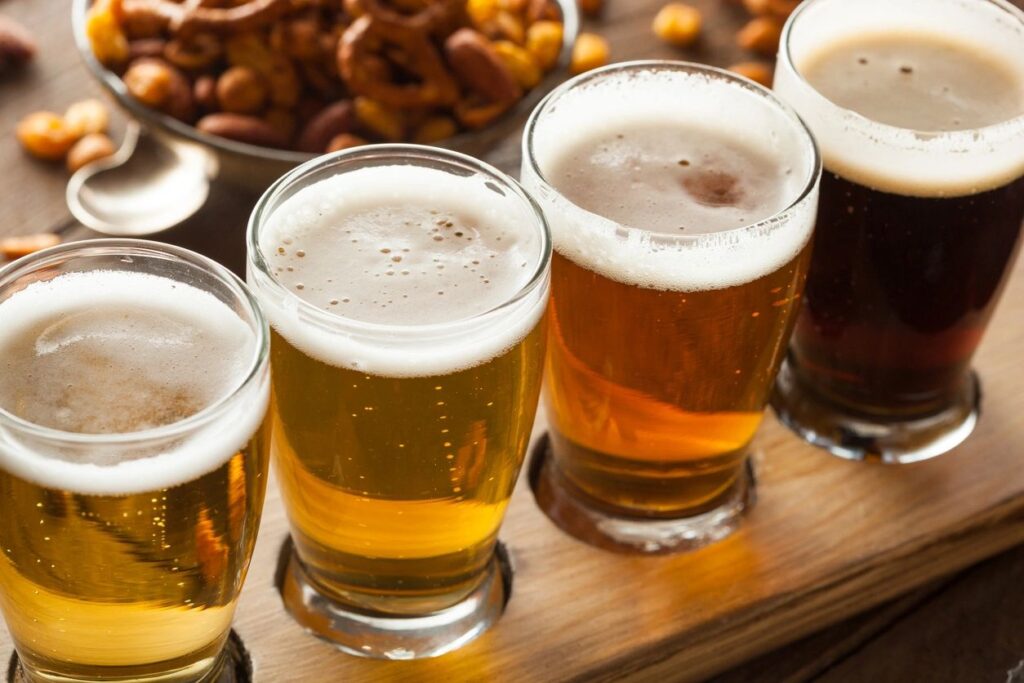 A flight of beer with nuts on a table in a brewery.