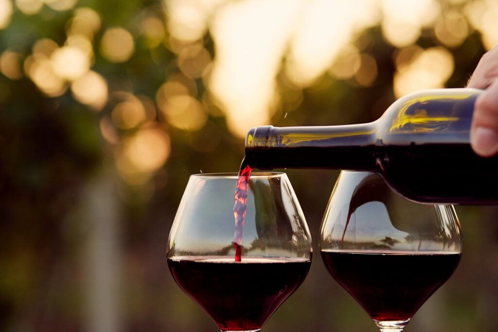 Wine getting poured into two glasses at a winery.